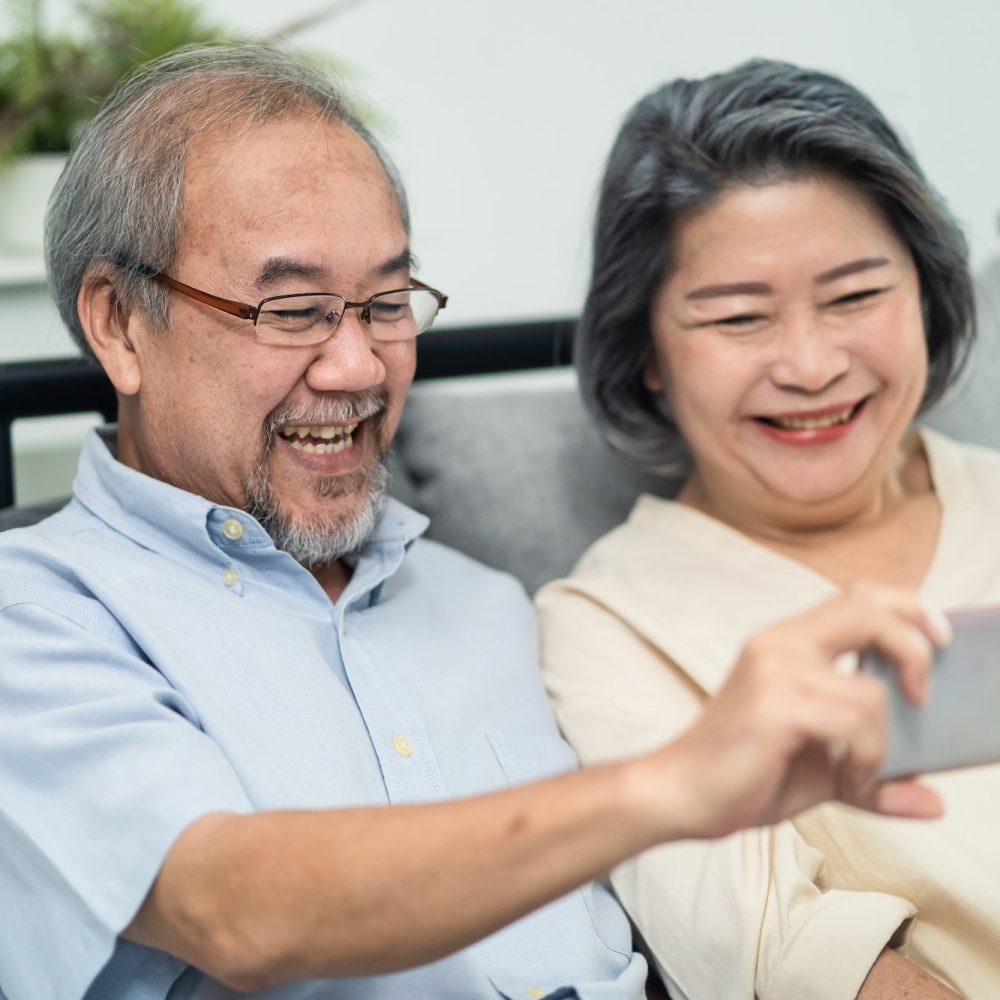 Asian old woman and old man hold mobile phone talking and smiling on video call with family